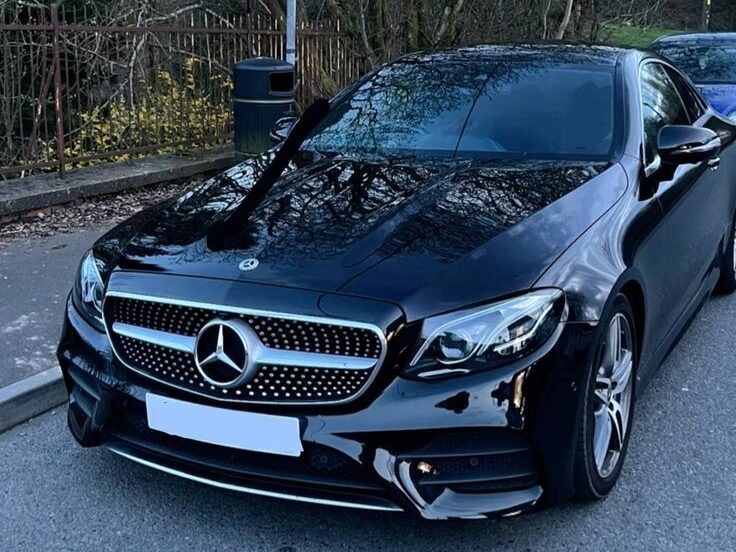 Black Mercedes-Benz sedan with reflective finish and signature grille shown on a laptop screen inside a website editor.