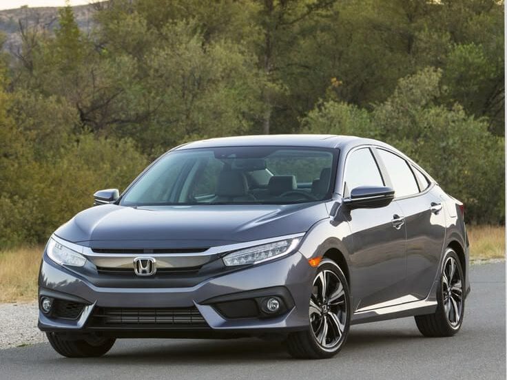 Front three-quarter view of a gray Honda Civic driving on a road.